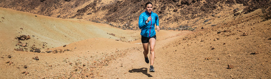A woman running through a sandy landscape.