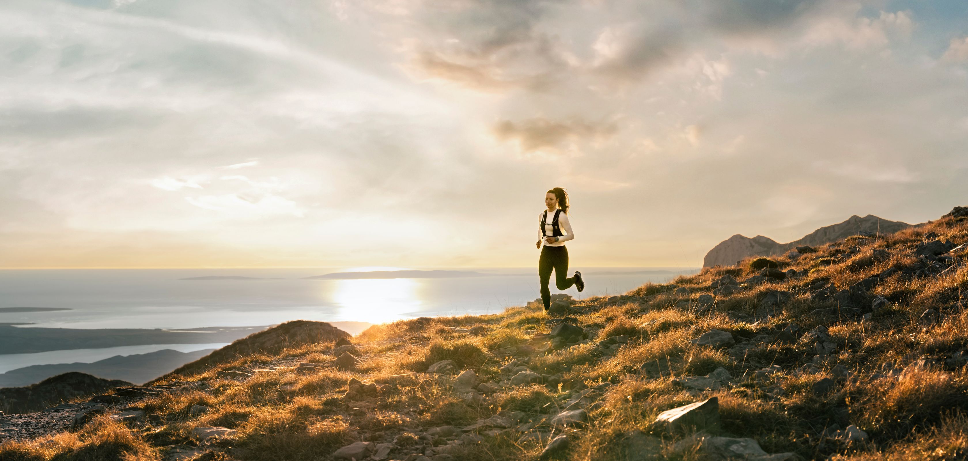A woman running at sunset on a cliff near the coast