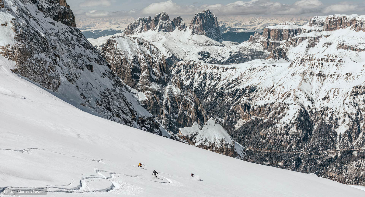 Luca Albrisi, Guido Trevisan and friends skiing down the snow and leaving fresh tracks on Marmolada, in Trentino-Alto Adige, Italy with rugged, majestic snow covered peaks in the distance. Photo by Matteo Pavana.