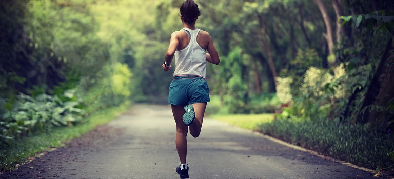 Female runner running at summer park trail . Healthy fitness woman jogging outdoors.