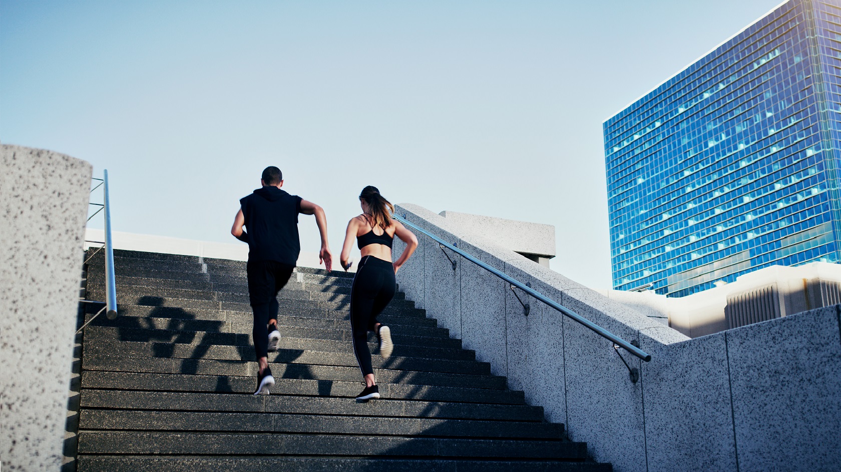 Rearview shot of a young man and woman running up stairs together in the city