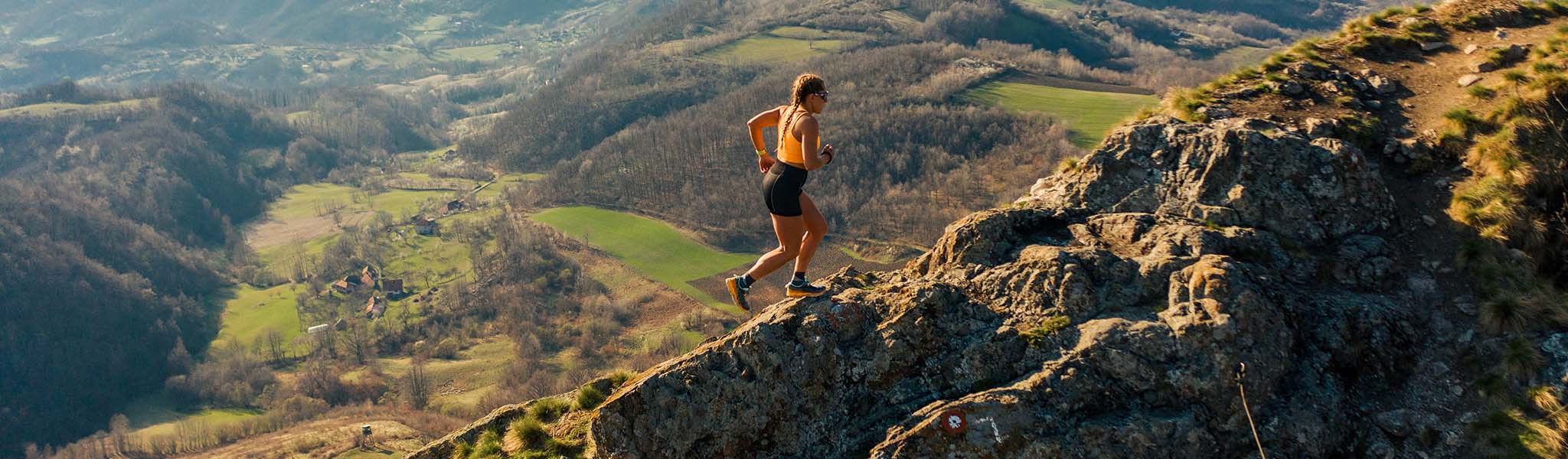 A woman trail running up a hill