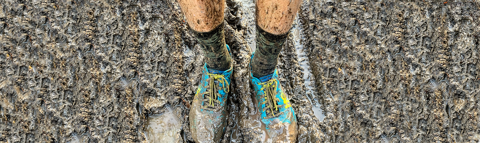 A man wearing muddy trail running shoes 