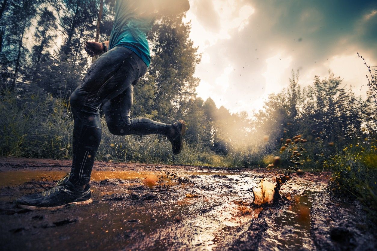 A person on a trail run through the mud 