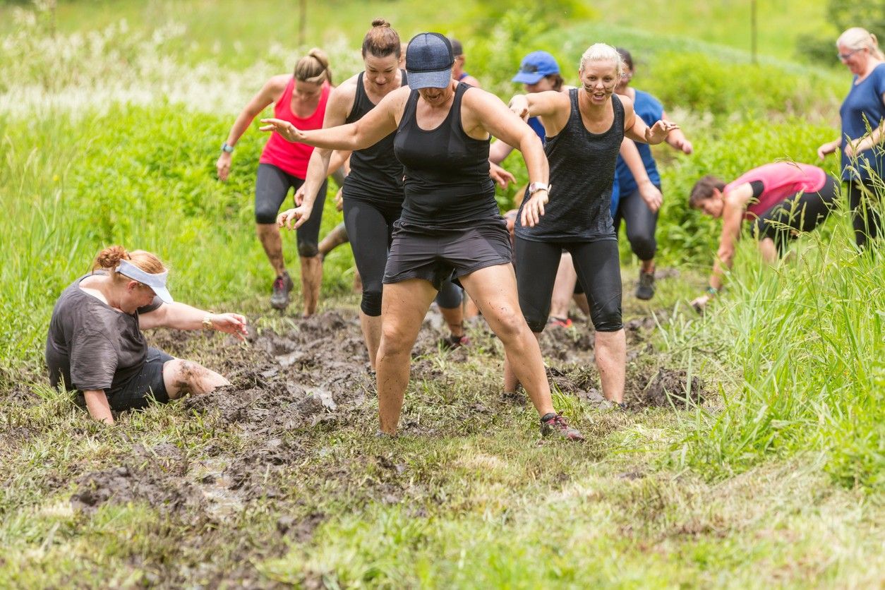 A group of people running through mud 