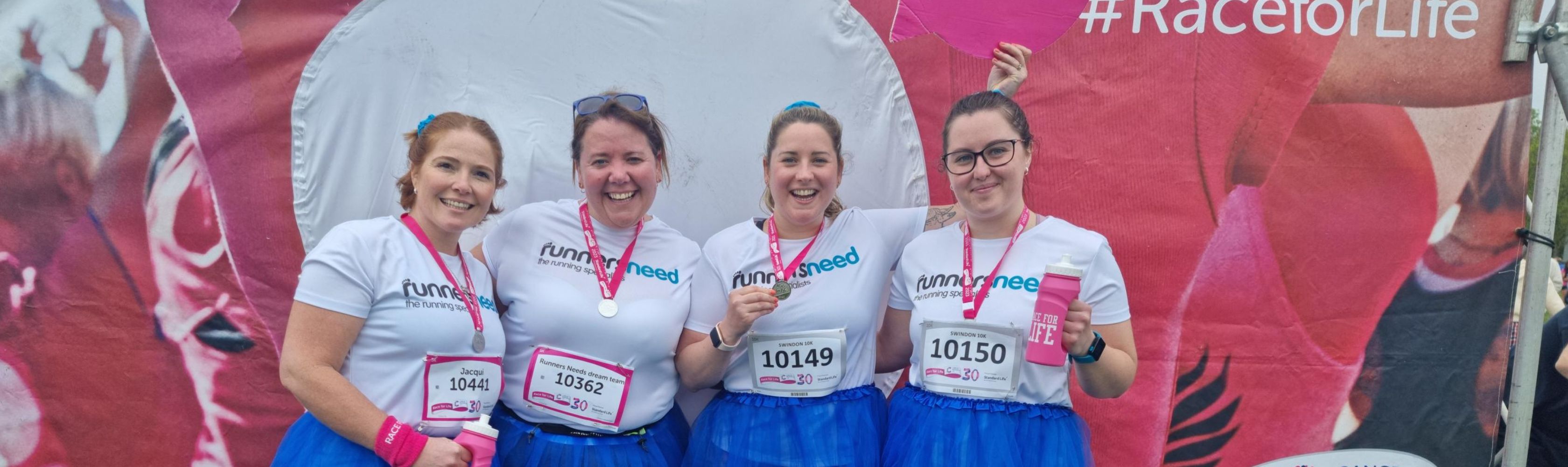 A group of runners standing in front of a race for life sign 