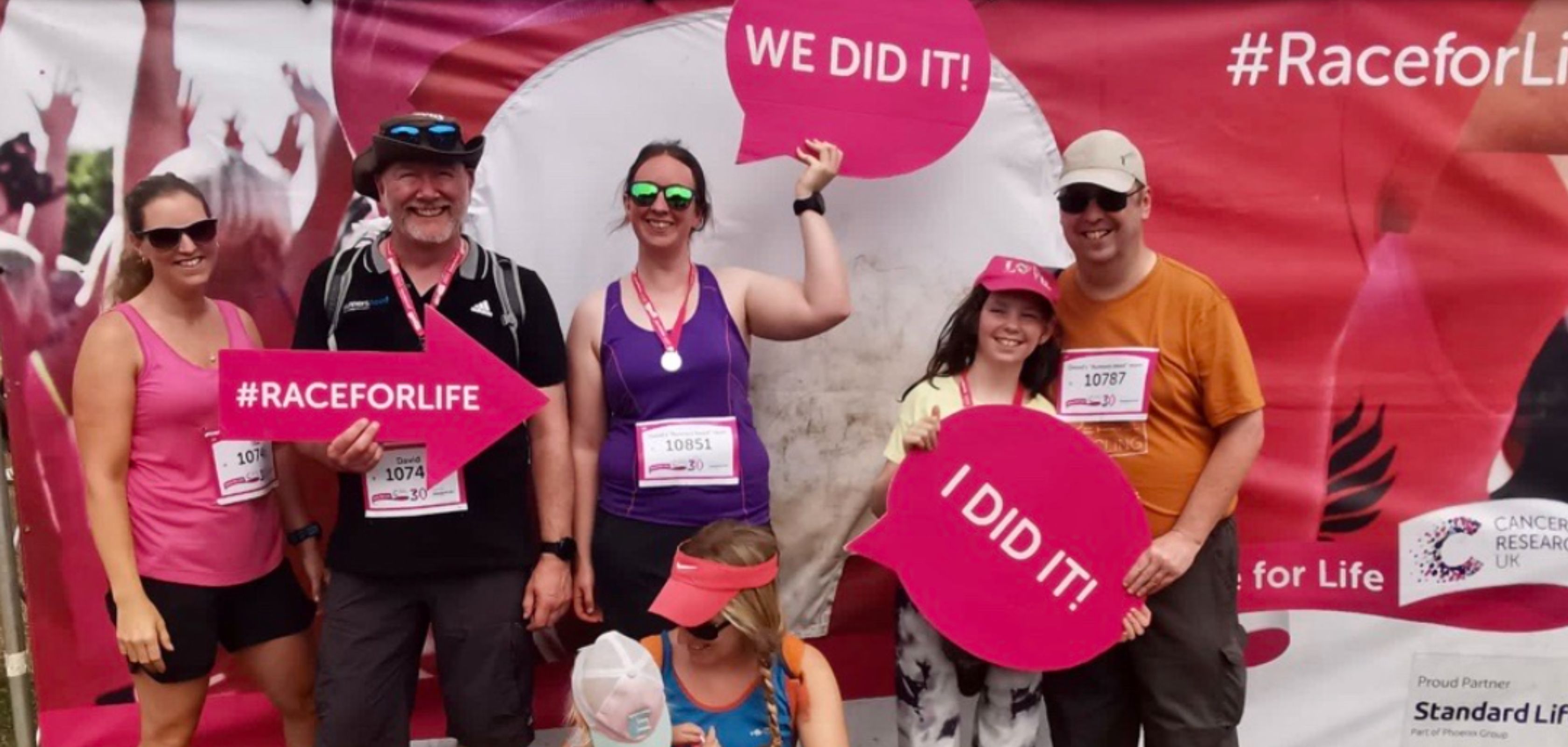 A group of runners standing in front of a race for life sign 