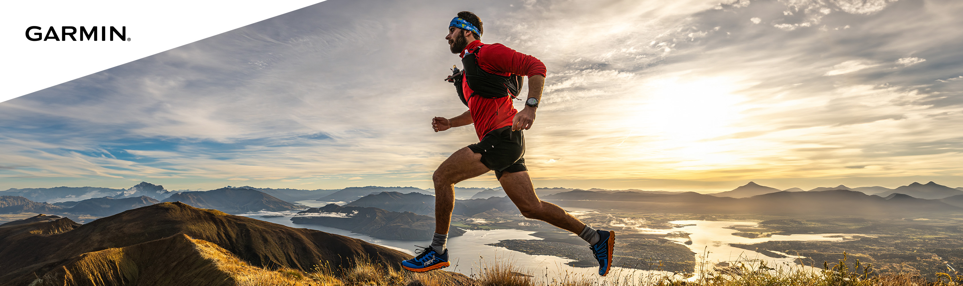 A man running across a hill top at sunset. Click to shop Garmin Enduro.