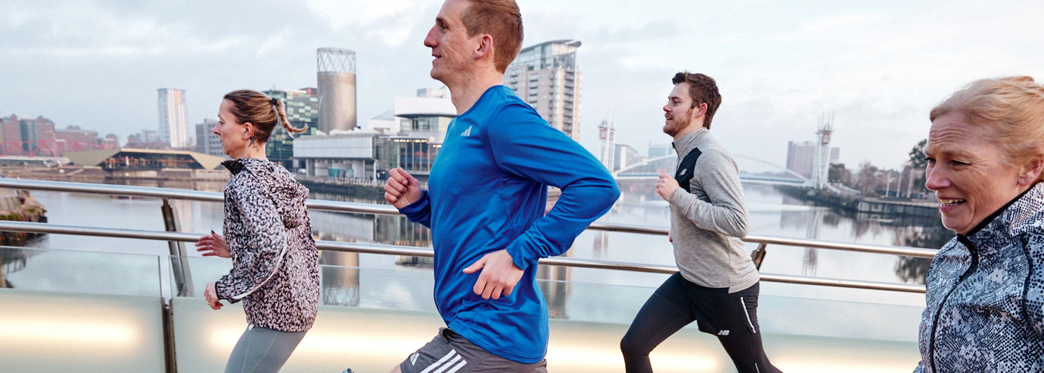 People are jogging in a town, wearing running shoes and running kit. 