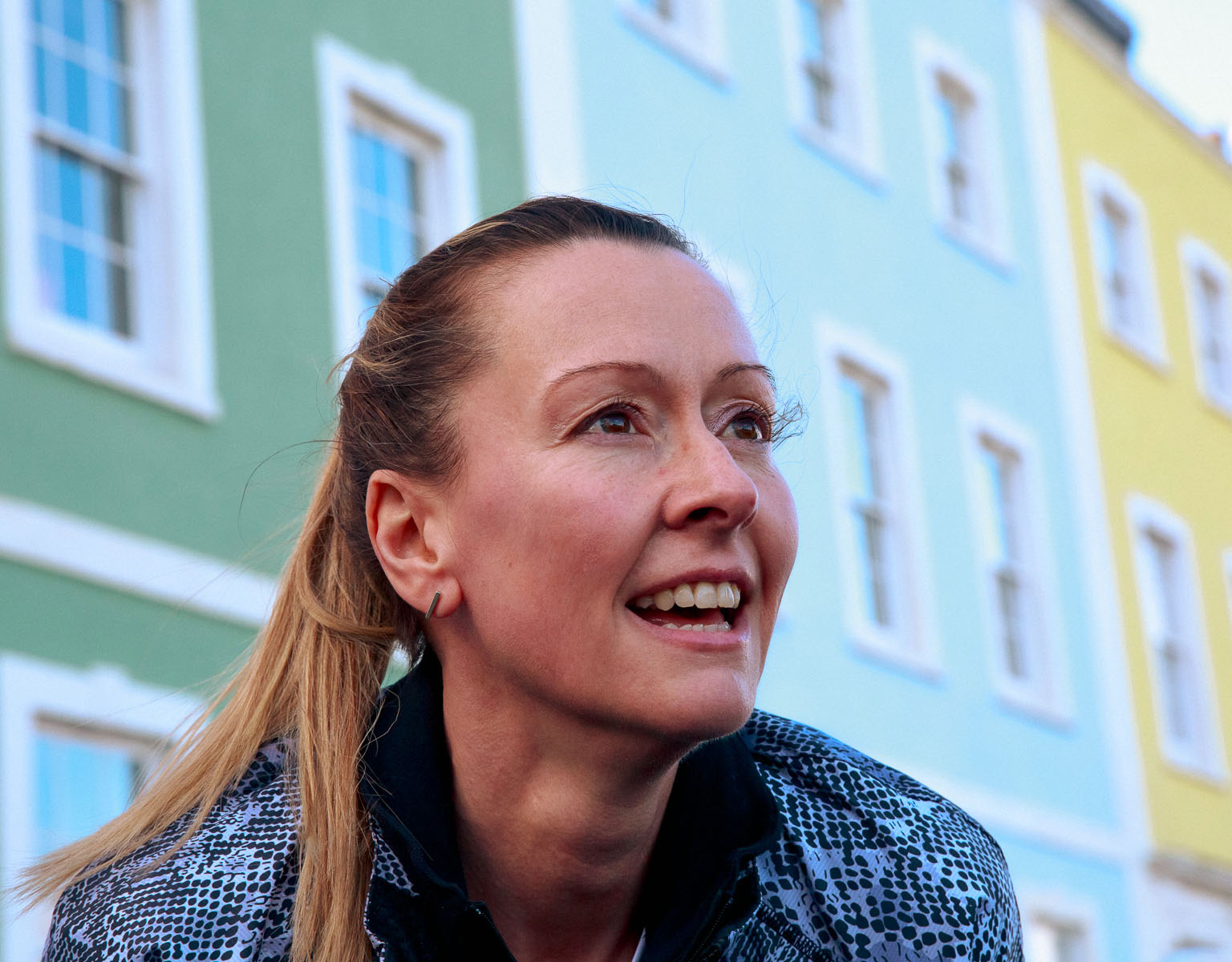 A woman's smiling face with a block of flats on the background. 