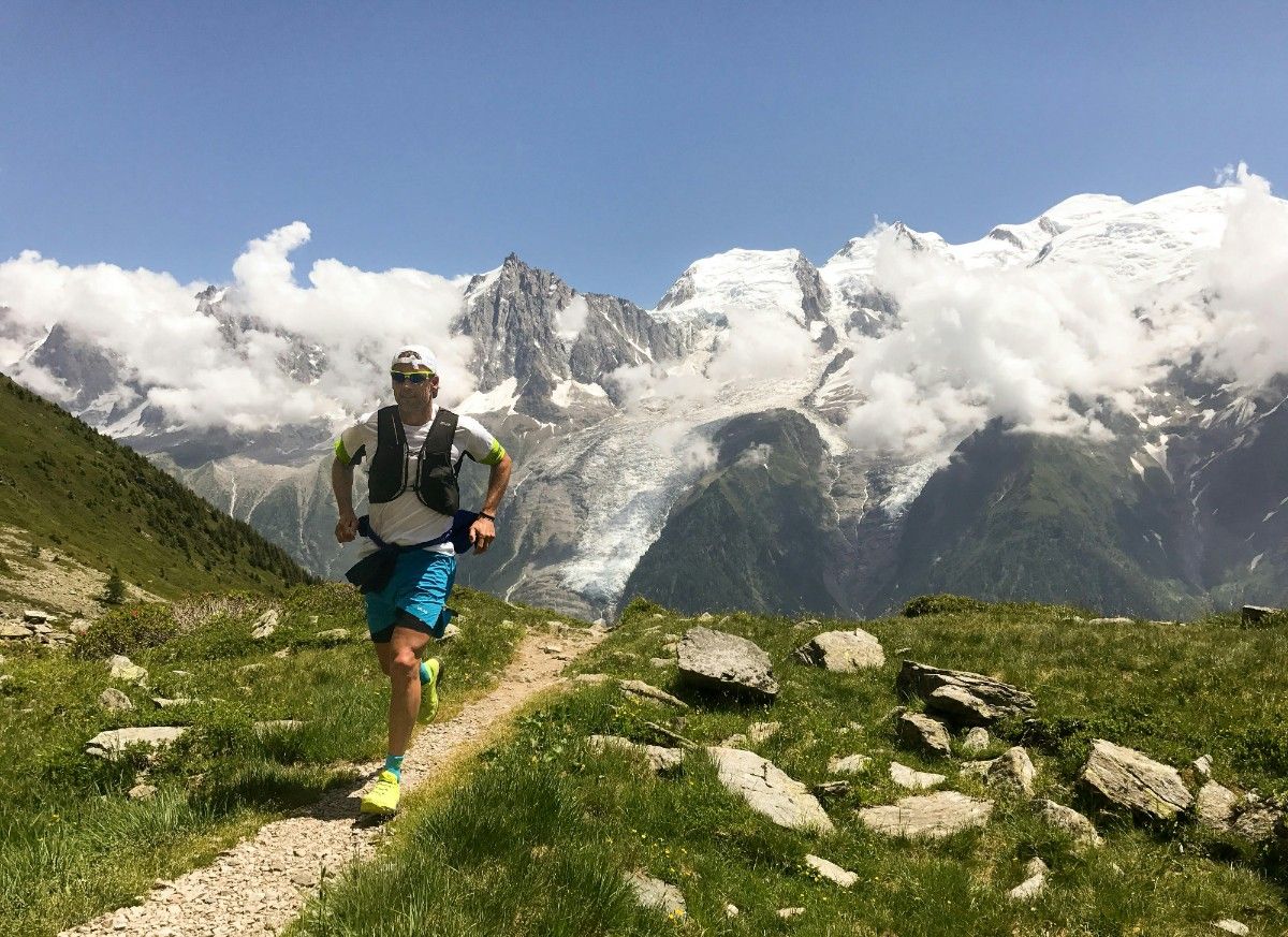 A man running through the mountains wearing a running cap