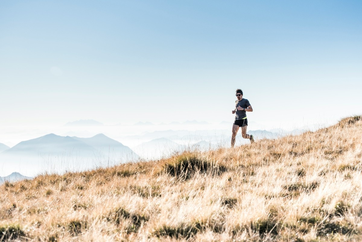 A man trail running on a hilly landscape