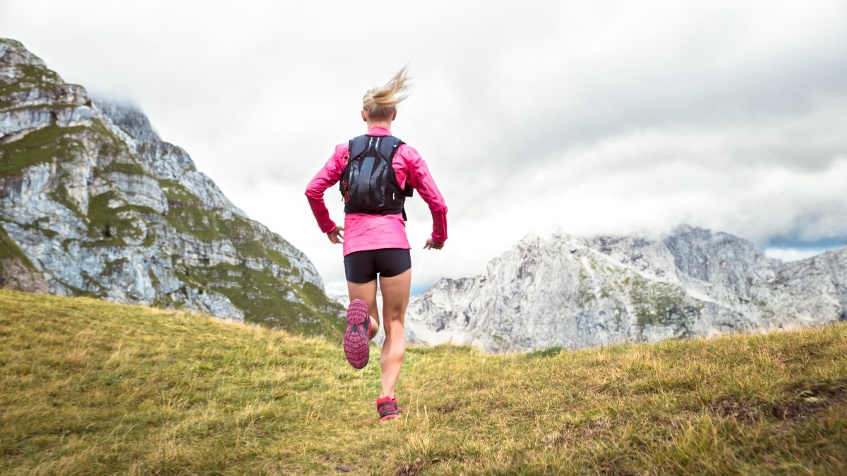 A woman trail running wearing a trail running pack 