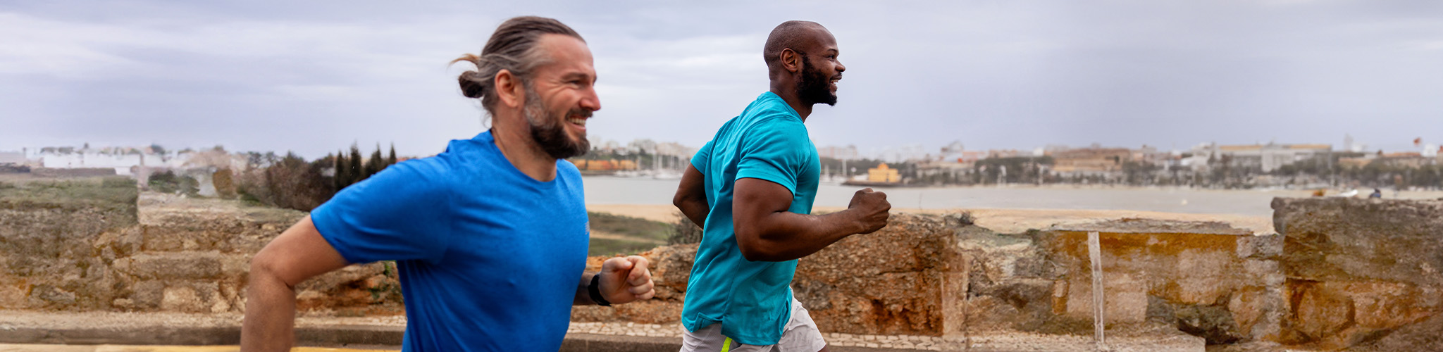 Shop men's new season. Two men running on the road