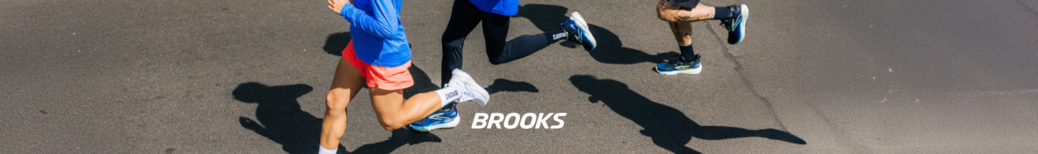 Shop Brooks. Group of people in Brooks gear running on the road