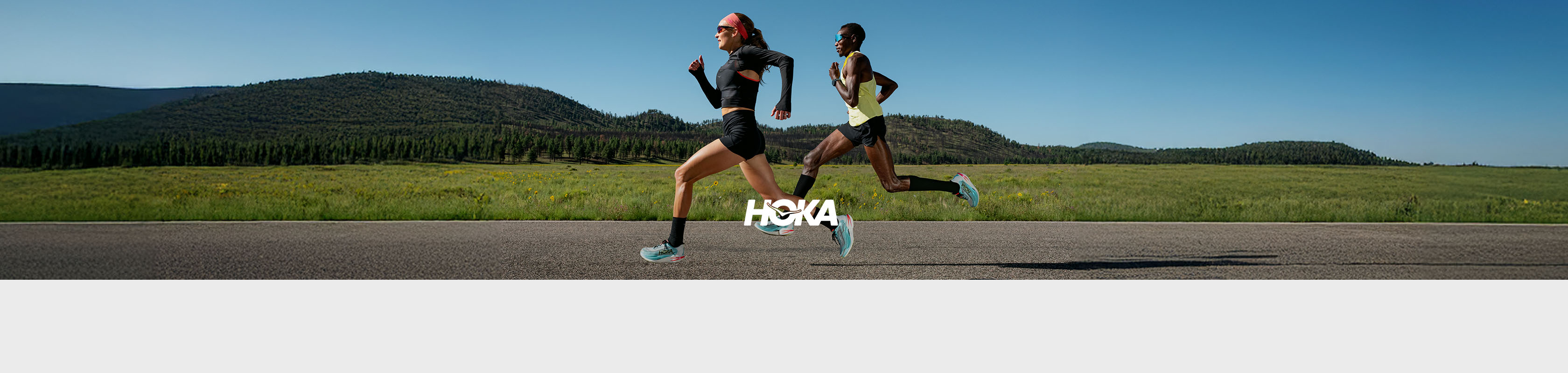 Shop The Hoka collection. Two runners in Hoka clothing and shoes running on a road