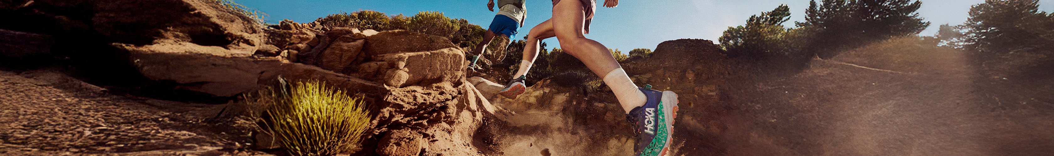 Shop trail running shoes. Two people running uphill
