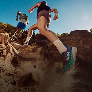 Shop trail shoes. Two runners running up a dirth path