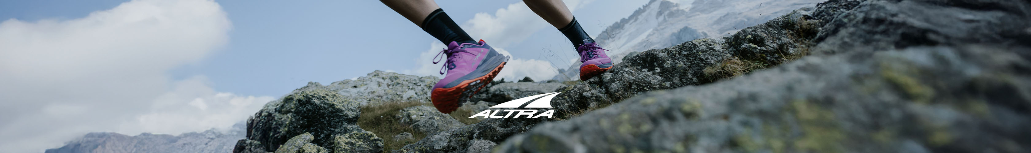 Shop Altra running shoes. A runner wearing Lone Peak running shoes on a trail path