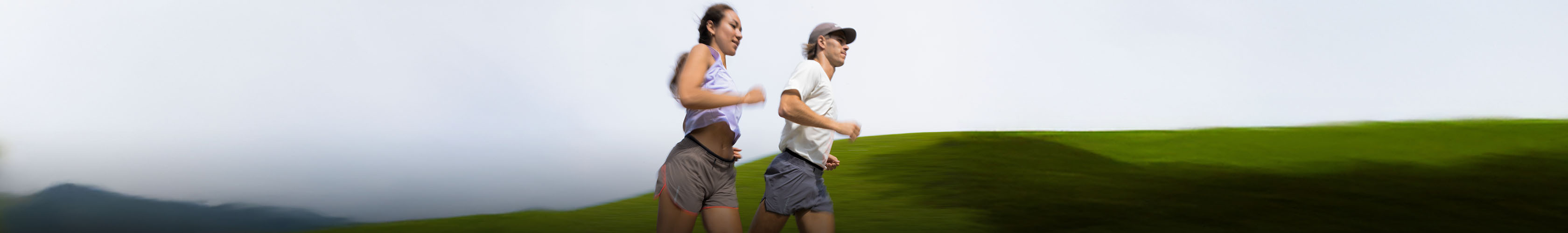 Shop Clothing. Man and woman in summer tops and shorts running on a road