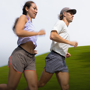 Shop Clothing. Man and woman in summer tops and shorts running on a road