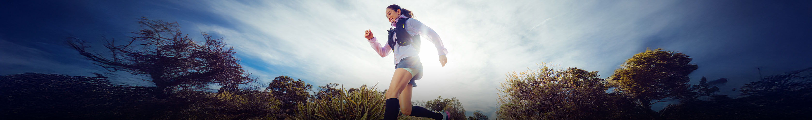 Shop trail running gear. A woman runnin on a trail path