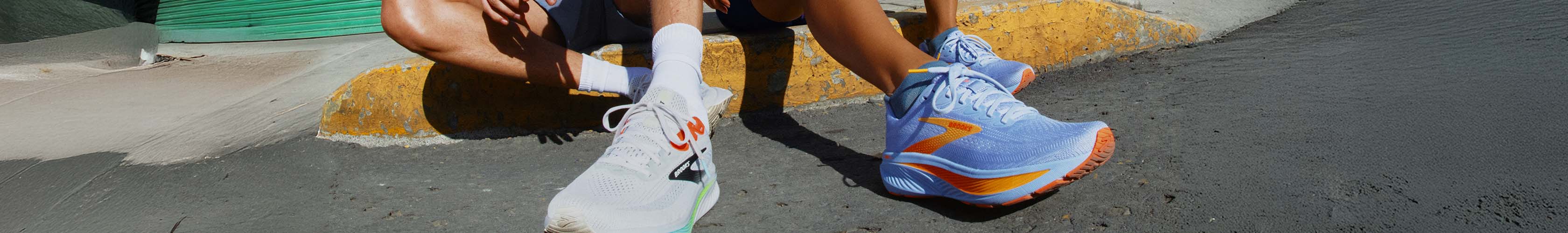 Shop new arrivals on Runners need. Two people in running shoes sitting on the edge of the road