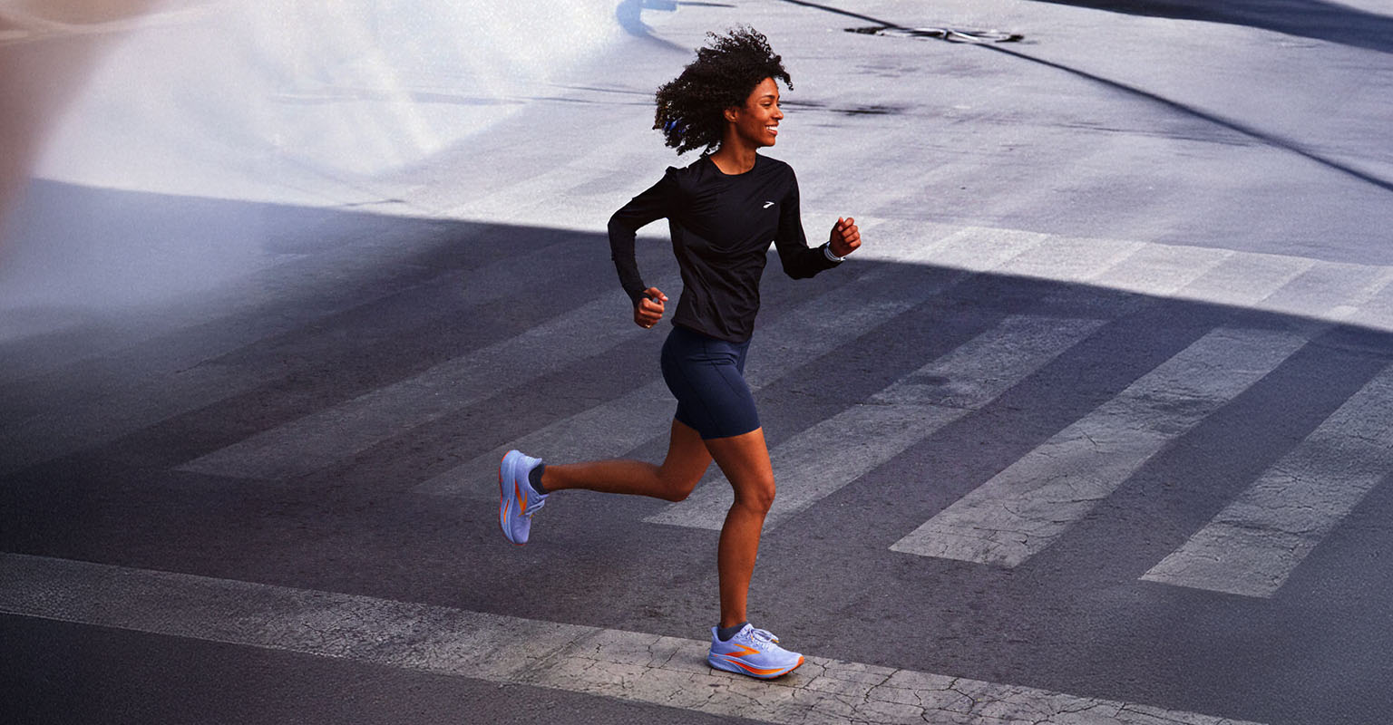 Shop women's running gear. A woman running across the street