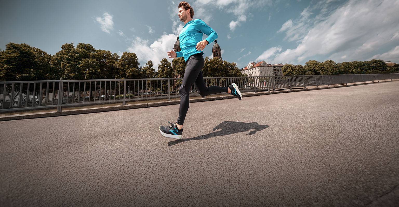 Shop men's running gear. A man running on a street