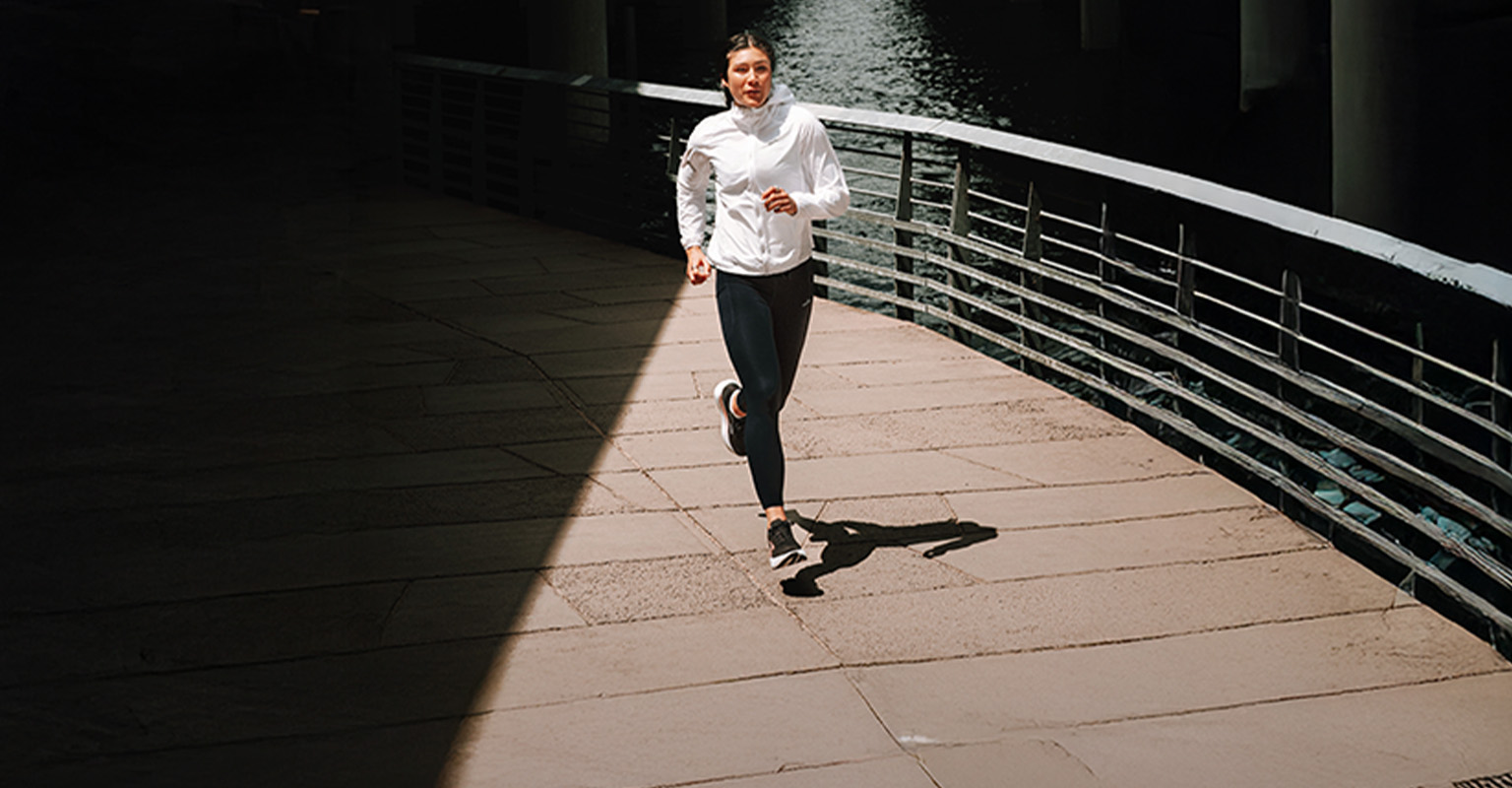 Shop women's running gear. A woman running on the street