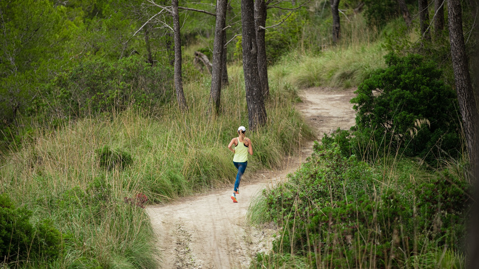 A trail runner running through a forest path 