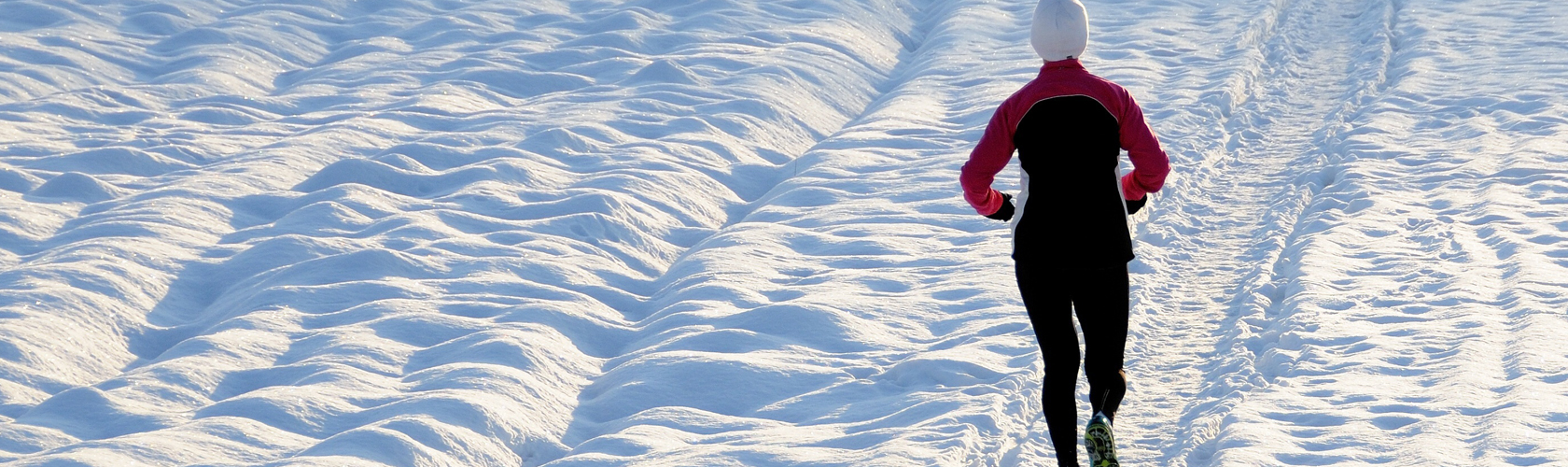 Winter running layering guide. A woman running ia a snow
